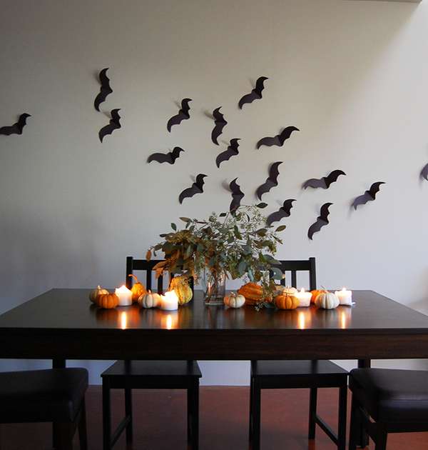 minimalist halloween decor and halloween tablescape using pumpkins, candles, and construction paper bats